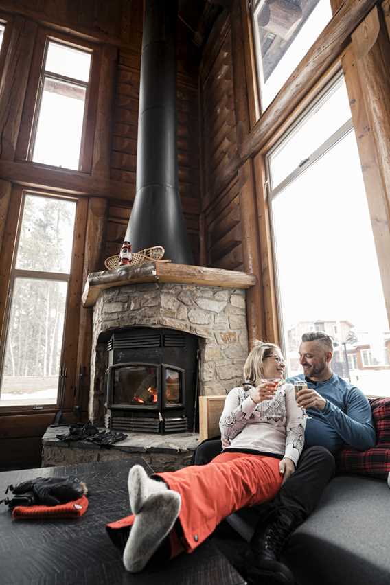 Couple prenant un verre sur le bord du foyer à l'Auberge du Lac Taureau